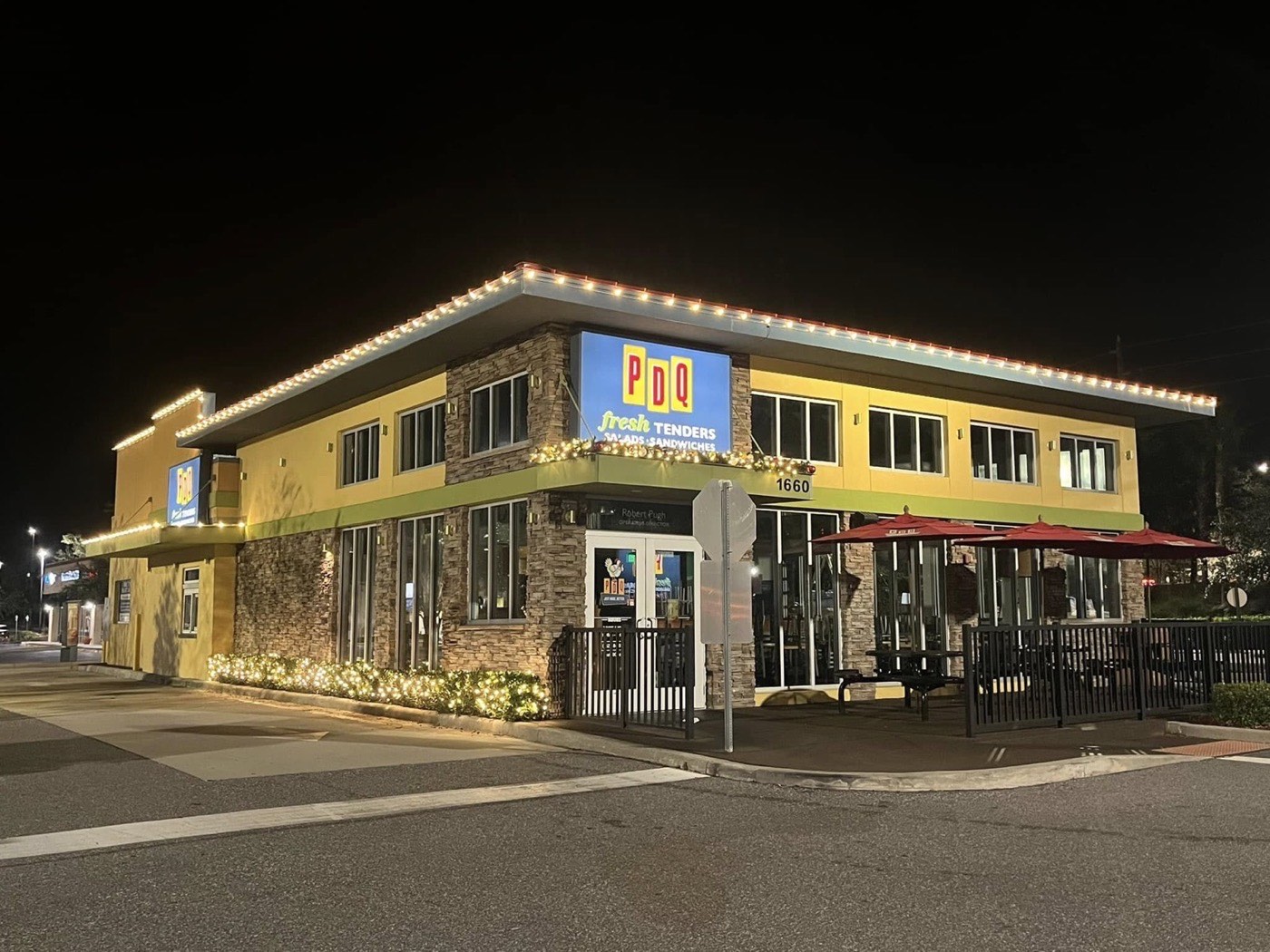 PDQ in Clermont at night with warm white roofline lighting and lit garland over the entry