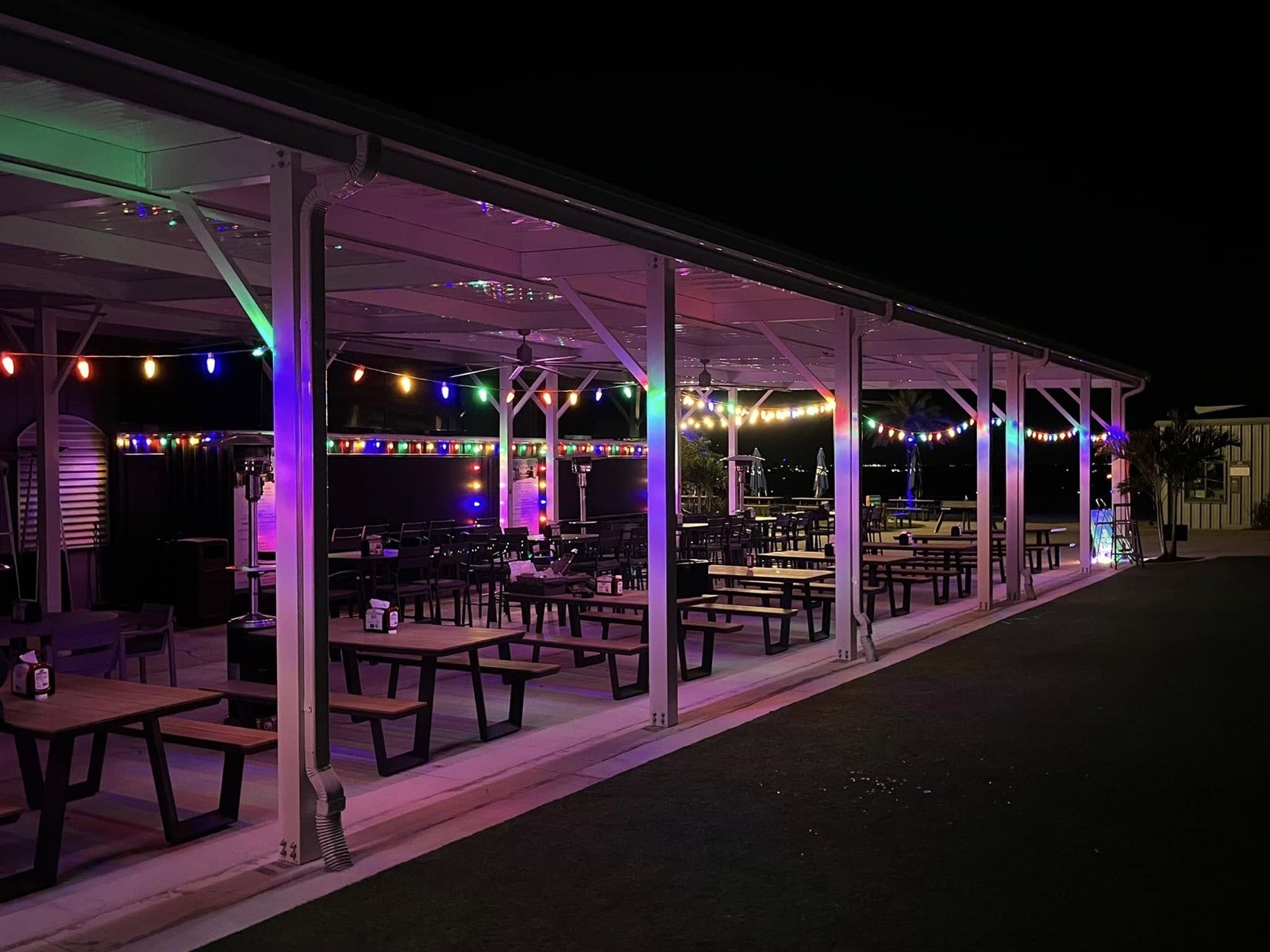 Patio at The View at Clermont National with multicolor holiday lights along the bar and rafters, glowing purple and festive at night
