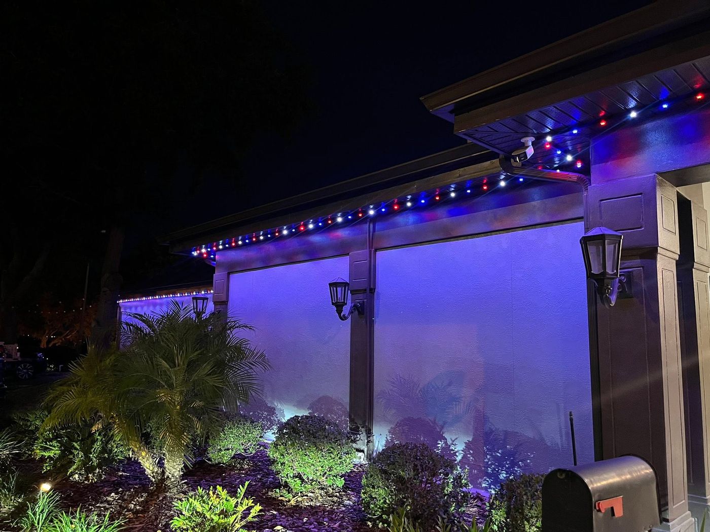 Permanent roofline lighting in red, white, and blue with purple landscape uplighting on a Florida home