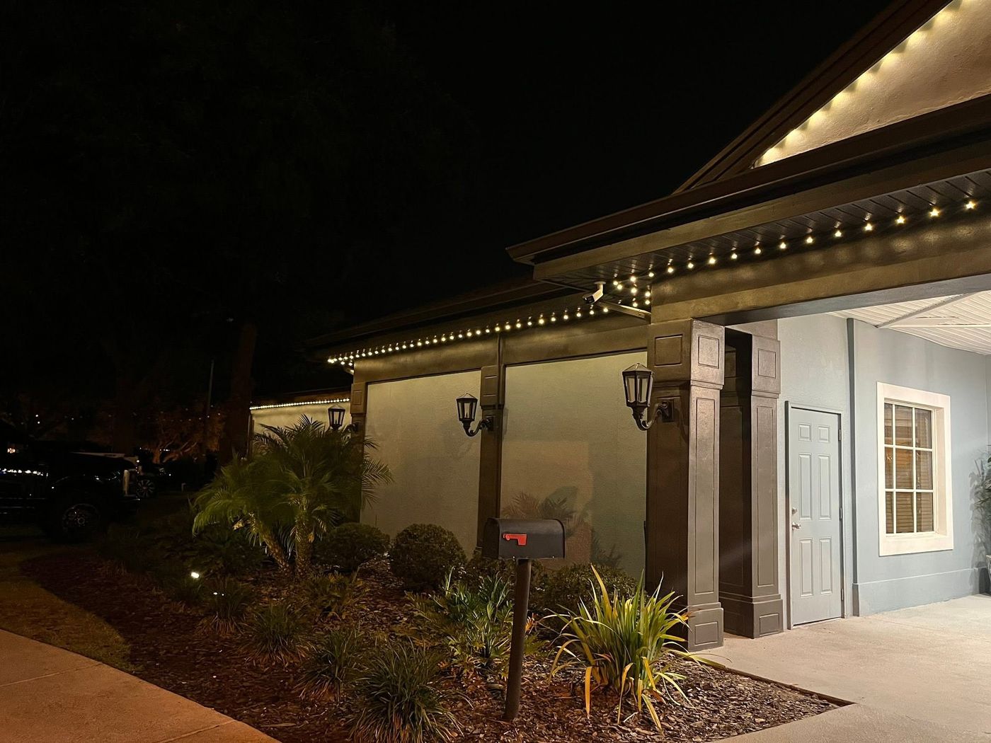 Permanent warm white eave lighting over a home entry at night