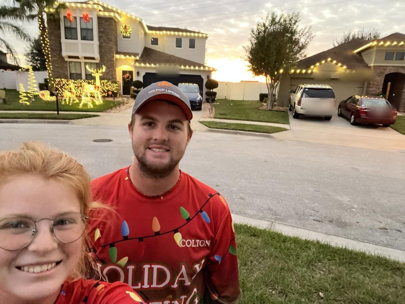 Owner Colton Lipham and a team member in Lipham Lighting holiday shirts in front of a freshly decorated home at sunset