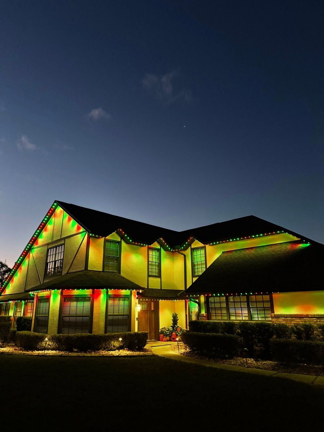 Two-story South Lake County home with red and green custom-cut holiday roofline lighting at night