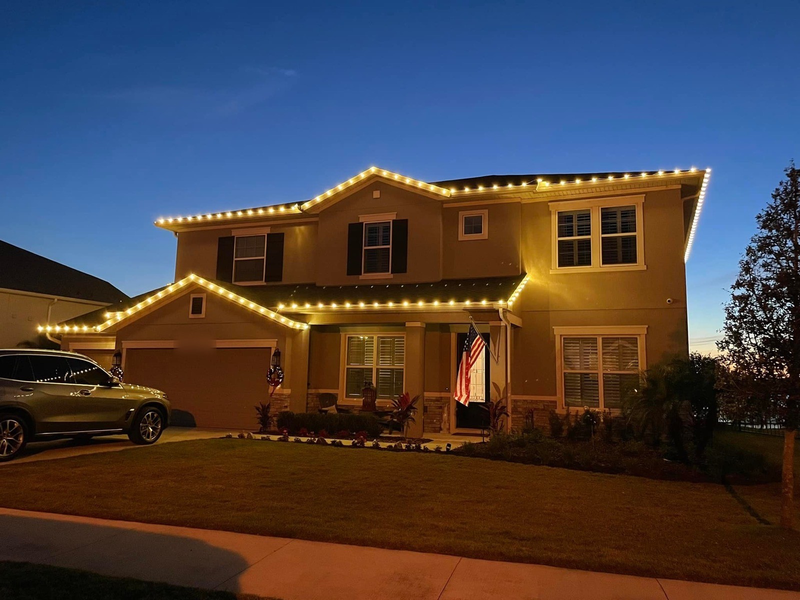 Two-story home with warm white roofline lighting in the deep blue hour
